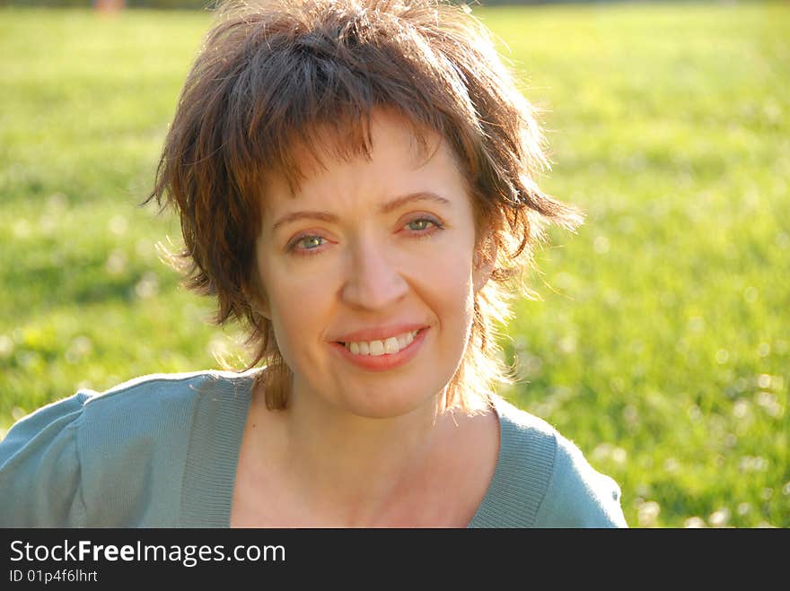 Woman sitting in the park looking at and smile to camera. Woman sitting in the park looking at and smile to camera