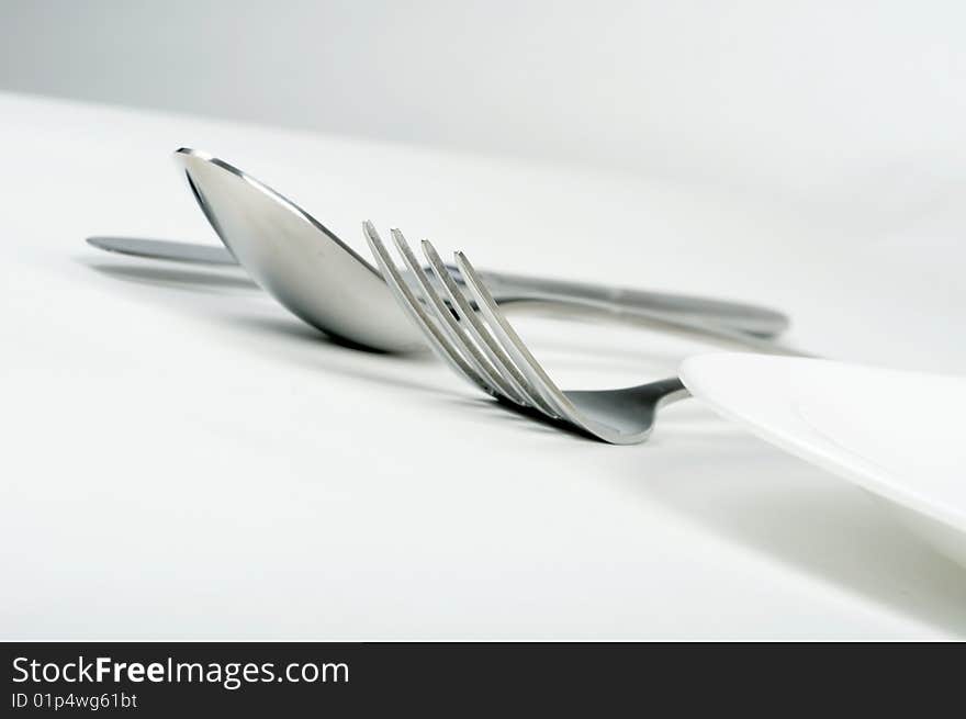 Fork, spoon and knife with white plate