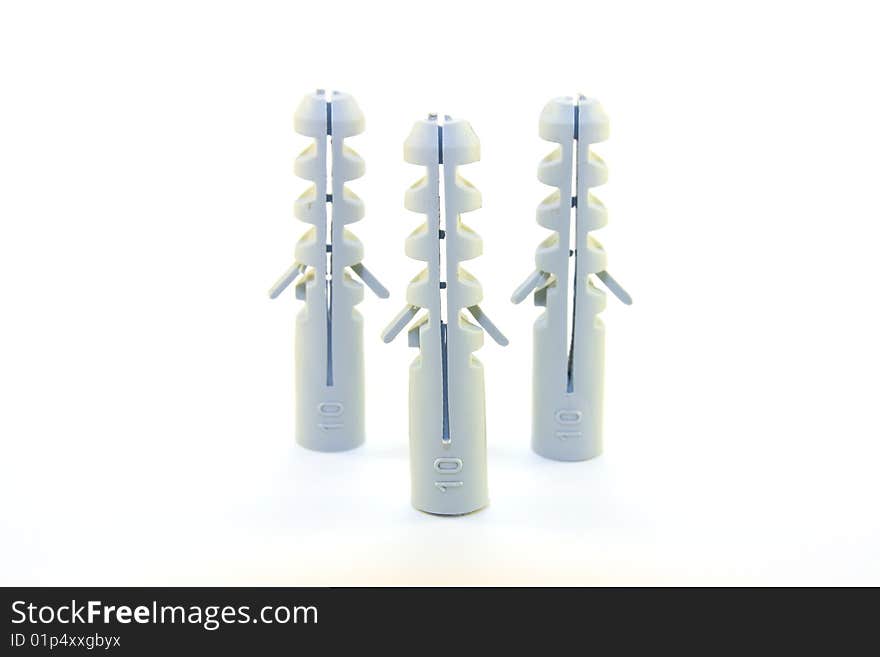 Three grey plastic wall plugs in a triangle on a white background. Three grey plastic wall plugs in a triangle on a white background