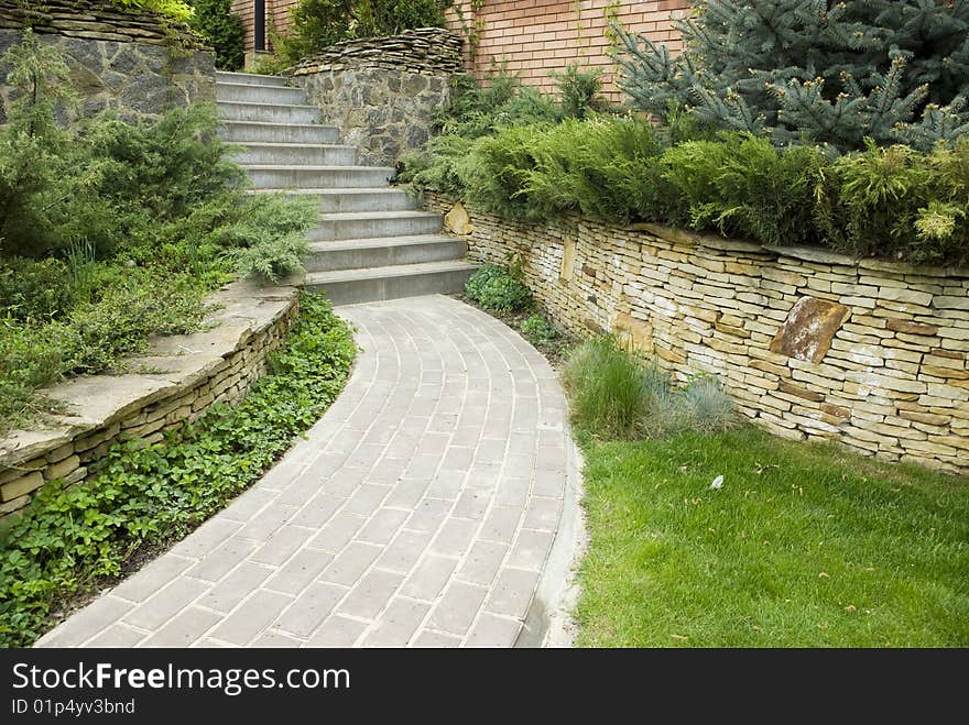 Garden stone path with grass growing up between the stones