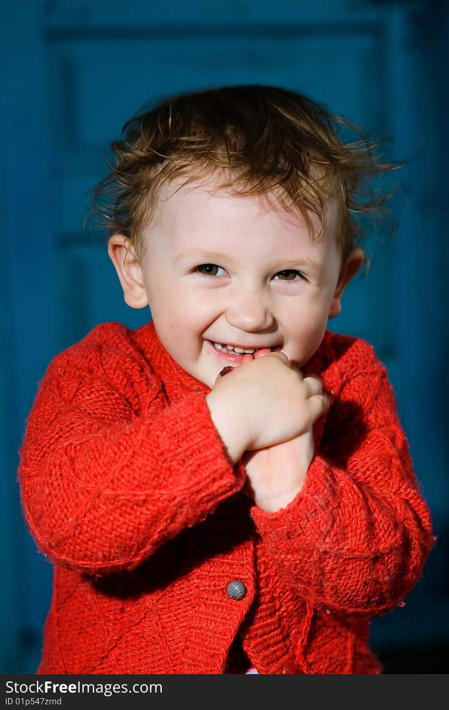 A smiling little boy  with dishevelled blond  hair on the blue background. A smiling little boy  with dishevelled blond  hair on the blue background