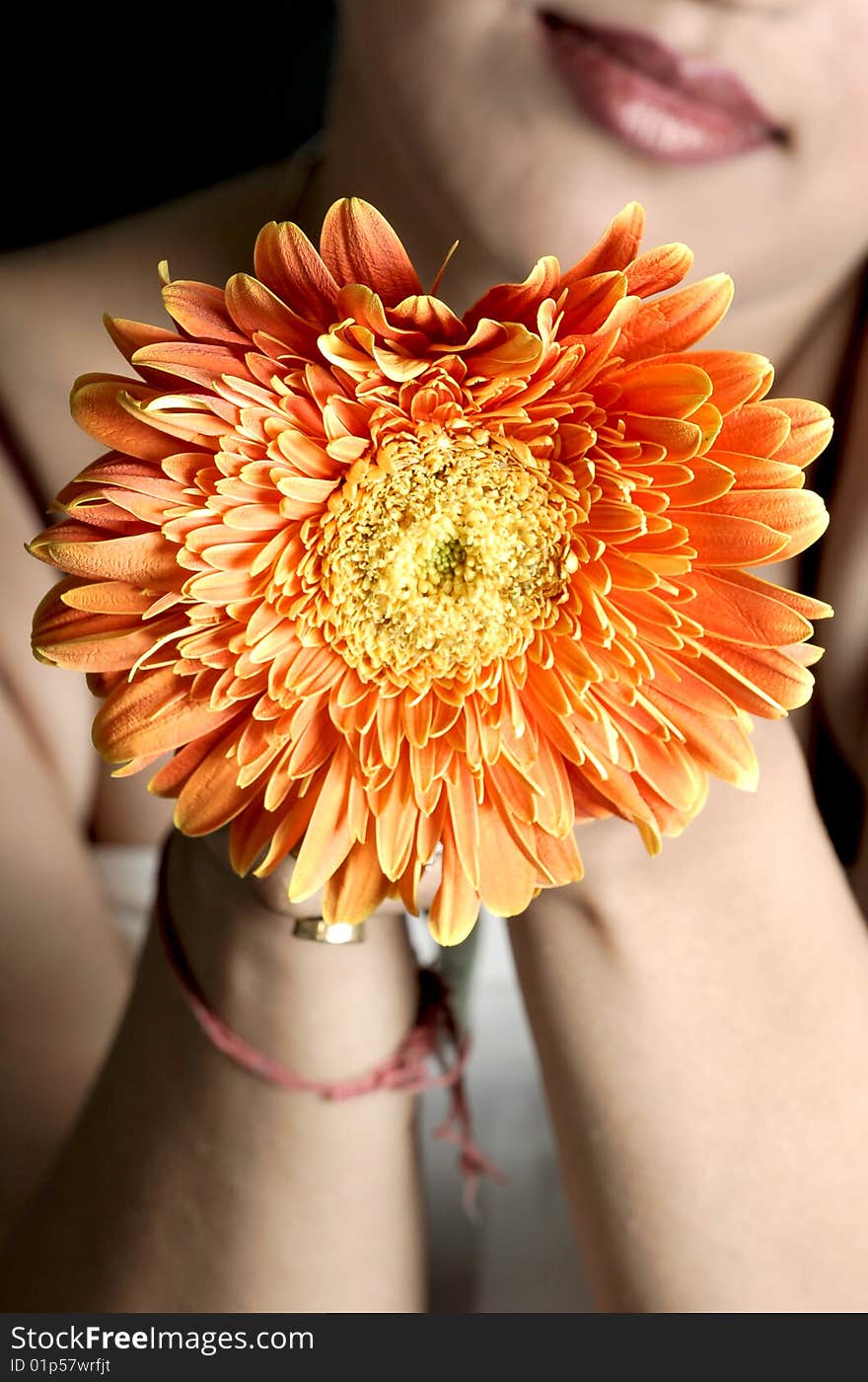 Model posing with flower in hands.