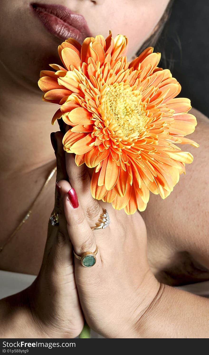 Model posing with flower in hands.