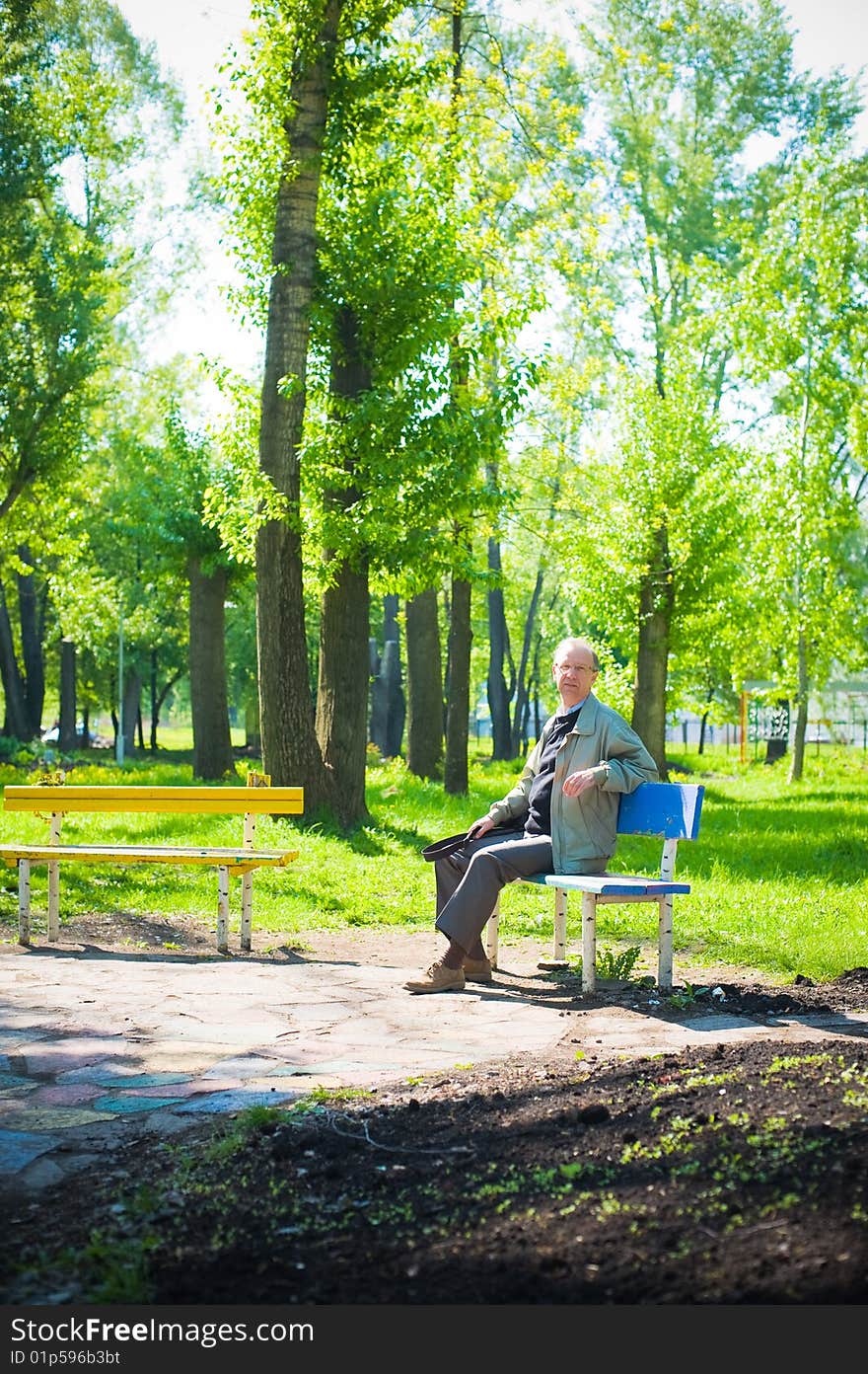 Mature man sits on a bench in park