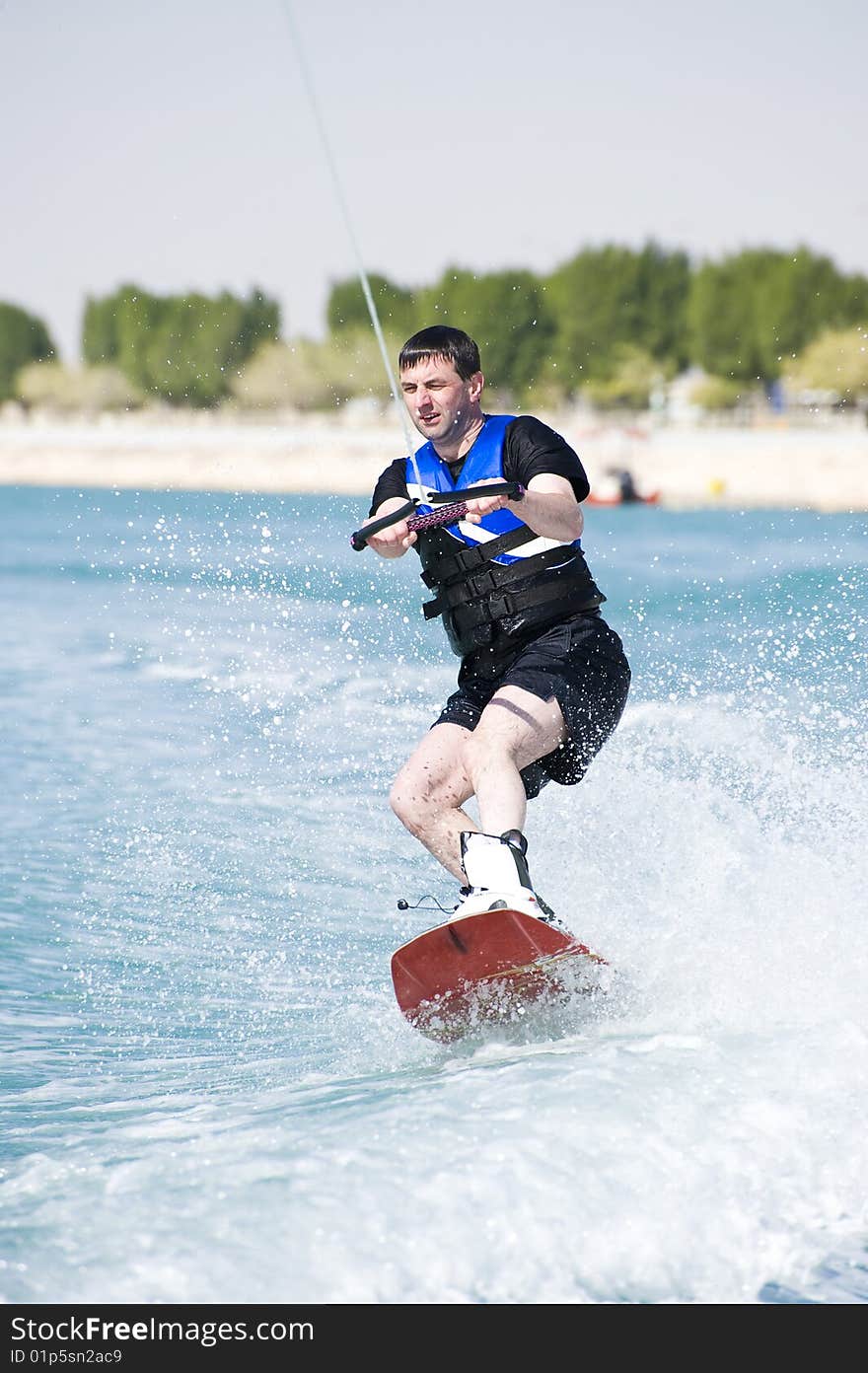 A wakeboarder enjoying the action of riding the wake of the boat. A wakeboarder enjoying the action of riding the wake of the boat.