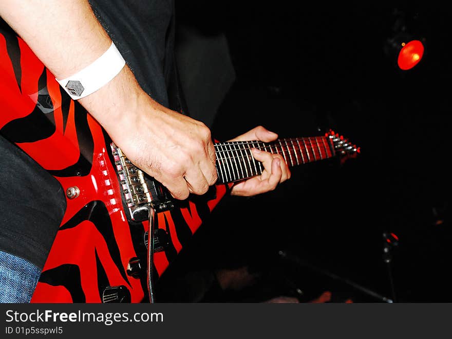 Guitarist with red electric guitar on stage performing. Guitarist with red electric guitar on stage performing