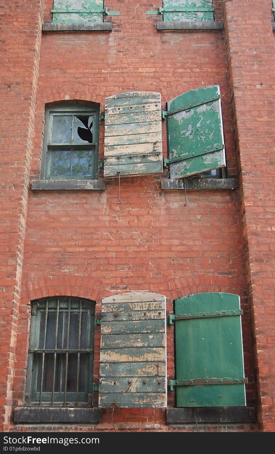 Old grungy abandoned brick building with falling shutters. Old grungy abandoned brick building with falling shutters