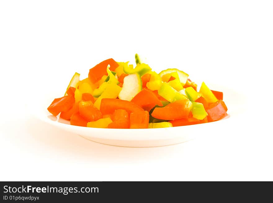 Red,Green and yellow chopped peppers on a plate on a white background