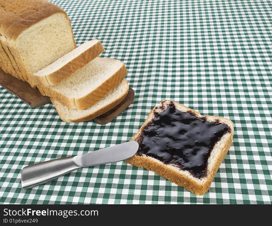 A slice of bread spread with jam beside the loaf of bread. A slice of bread spread with jam beside the loaf of bread.