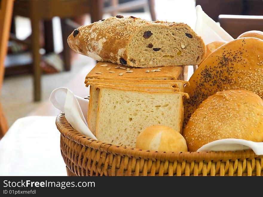 A variety of freshly baked breads served in a basket in a restaurant. A variety of freshly baked breads served in a basket in a restaurant