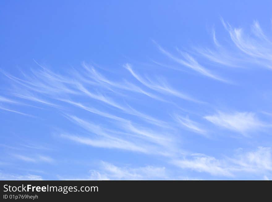 Thin, whispy clouds forming an unusual pattern against a medium-blue sky. Thin, whispy clouds forming an unusual pattern against a medium-blue sky