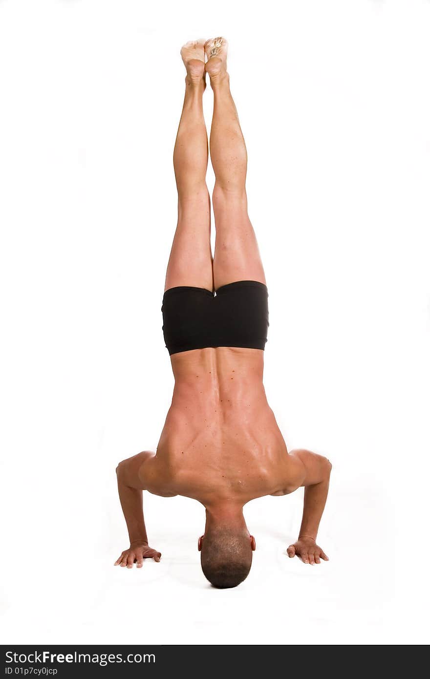 Young sportsman head-standing . Isolated over white background.