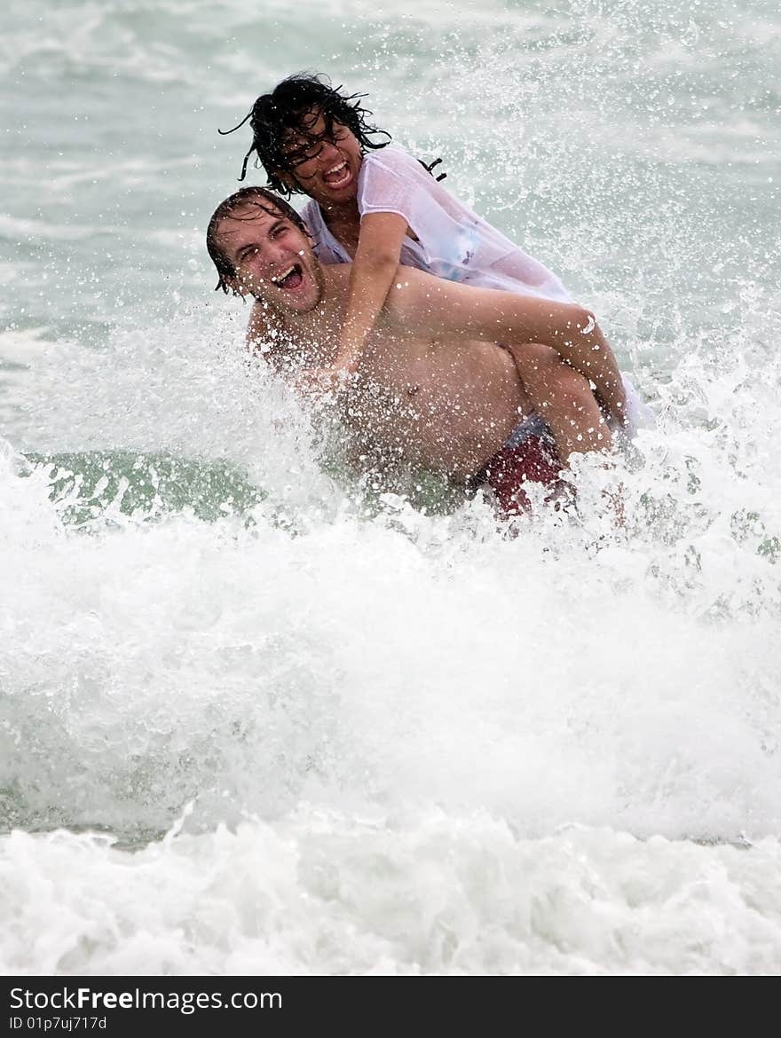 Couple having fun in the water. Splashing waves. Couple having fun in the water. Splashing waves.