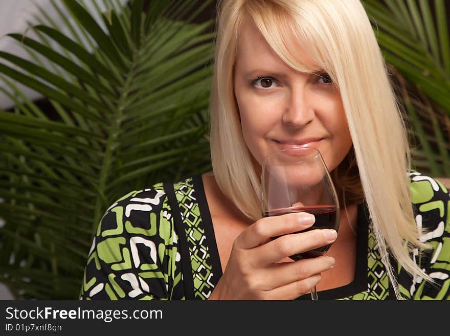 Beautiful blonde smiling woman at an evening social gathering tasting wine. Beautiful blonde smiling woman at an evening social gathering tasting wine.