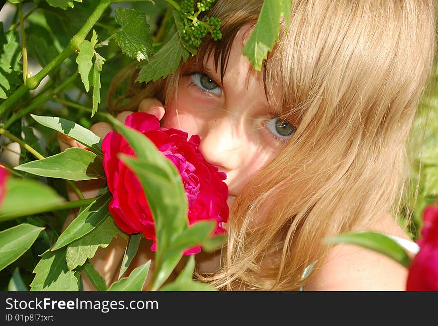 Girl smelling a single red peony outdoors. Girl smelling a single red peony outdoors