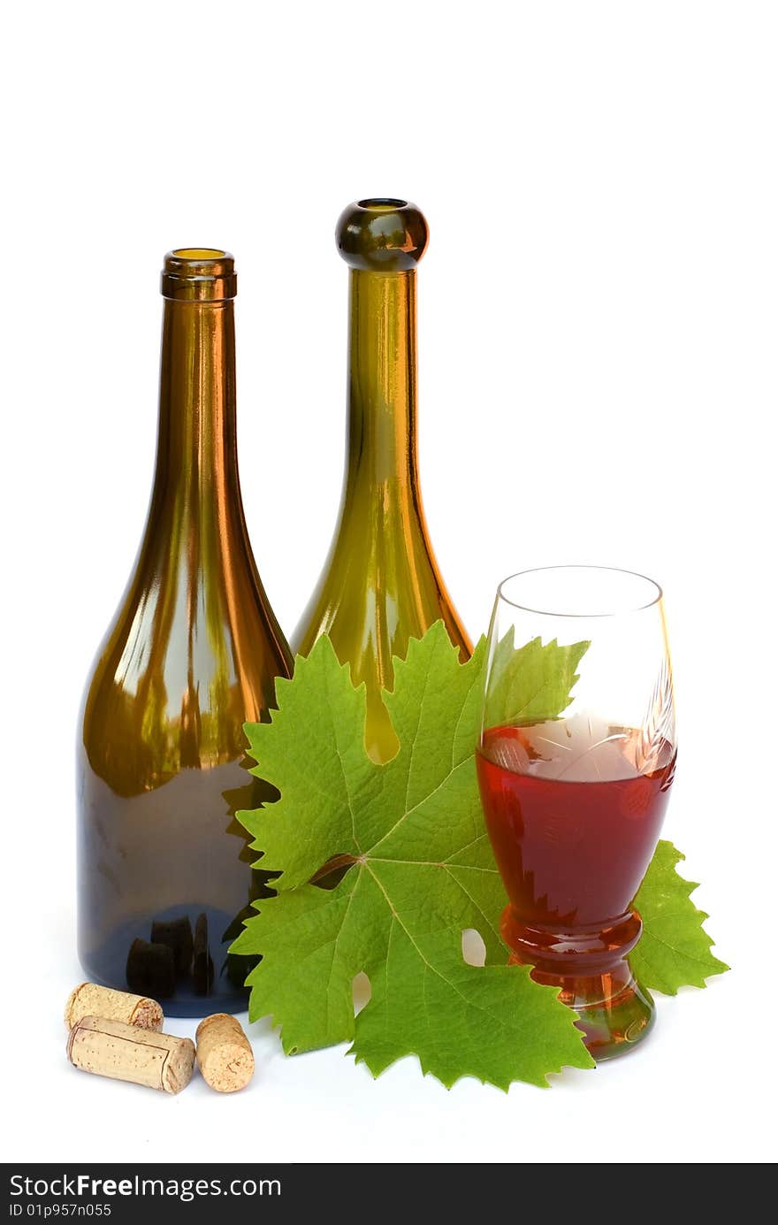 Still-life with two wine bottles, a glass of wine and grape sheet on a white background