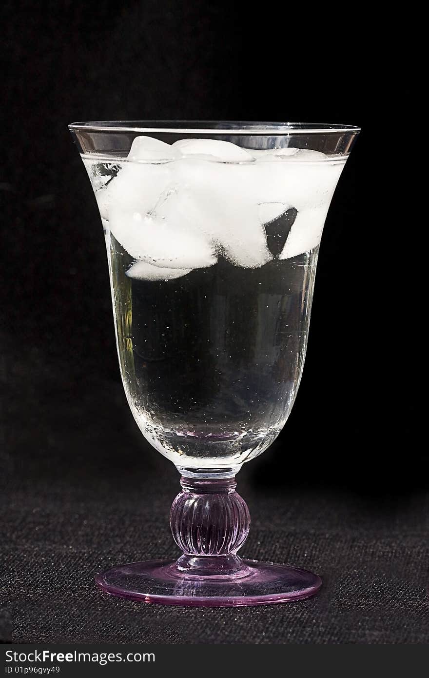 Glass of ice water with ice cubes on a black background. Glass of ice water with ice cubes on a black background