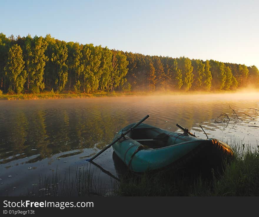 Early foggy morning of 31 May 2009. The boat on the coast of a lake. Golden fog on the back background. Russia, Spring 2009.