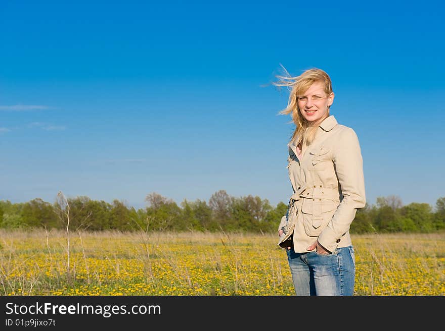 The young smiling girl standing on field. The young smiling girl standing on field