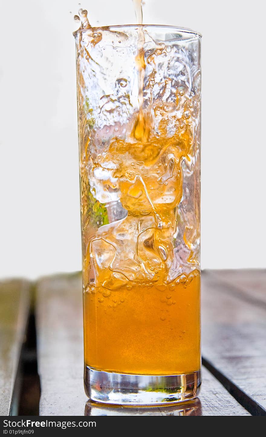 Cold orange drink poured into glass with ice cubes. Cold orange drink poured into glass with ice cubes