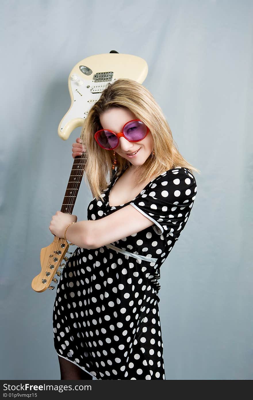 Blonde with guitar smiling isolated over grey background