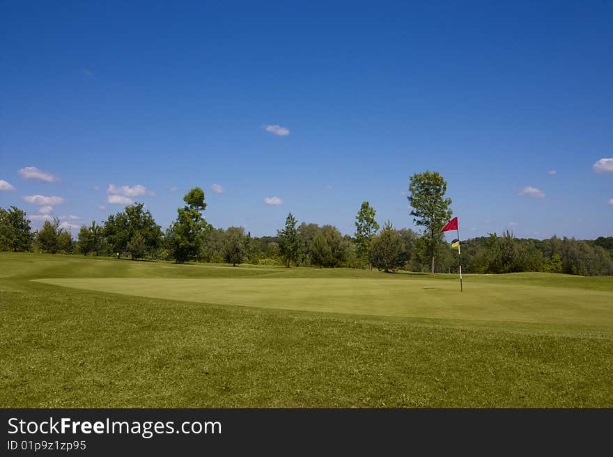 Red flag on hole, golf course tee