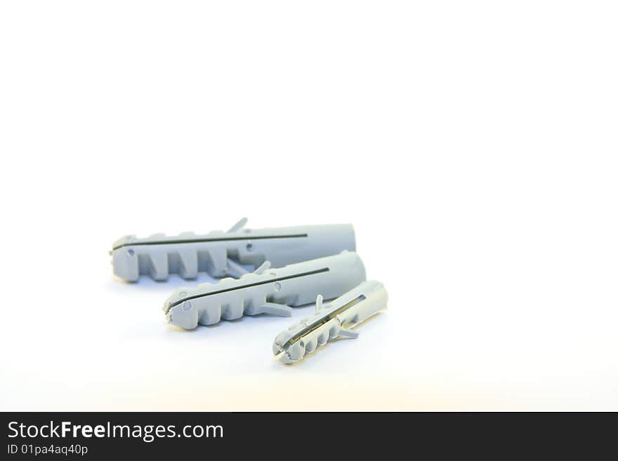 Three grey plastic wall plugs lying down on a white background. Three grey plastic wall plugs lying down on a white background