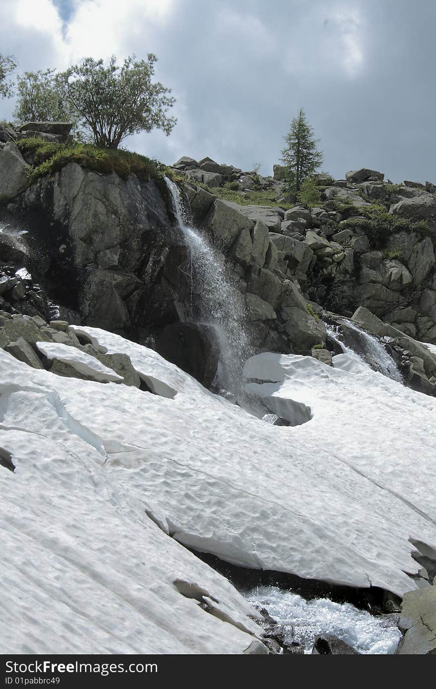 Spring, high rock with a bush, a falls, snow. Spring, high rock with a bush, a falls, snow.