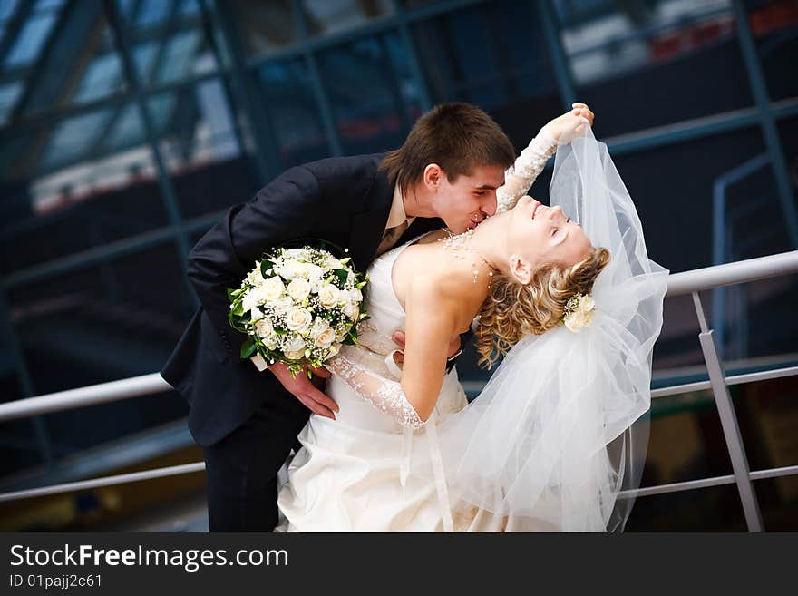 Groom and bride kiss under the glass ceiling