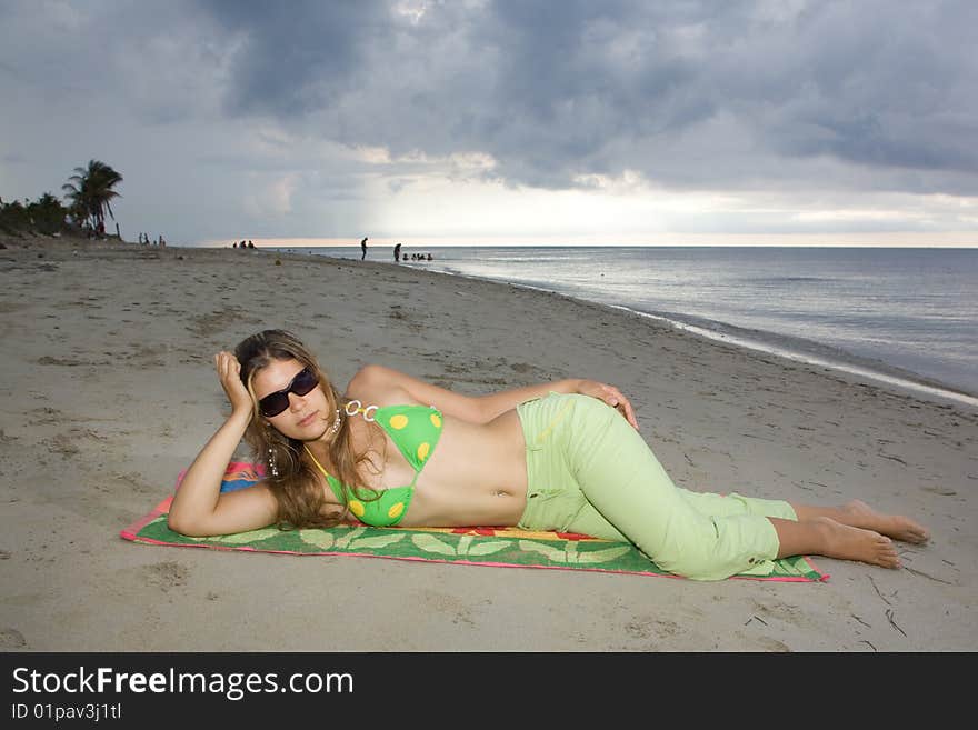Beautiful lady relaxing in the beach, laying on a coloured towel. Beautiful lady relaxing in the beach, laying on a coloured towel
