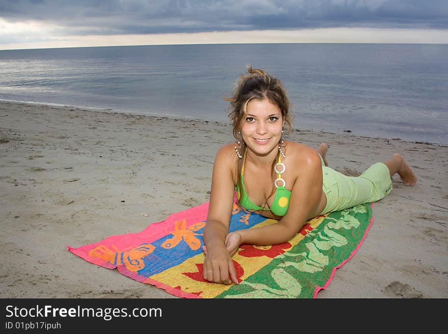 Beautiful lady smiling in the beach, laying on a coloured towel (II). Beautiful lady smiling in the beach, laying on a coloured towel (II)