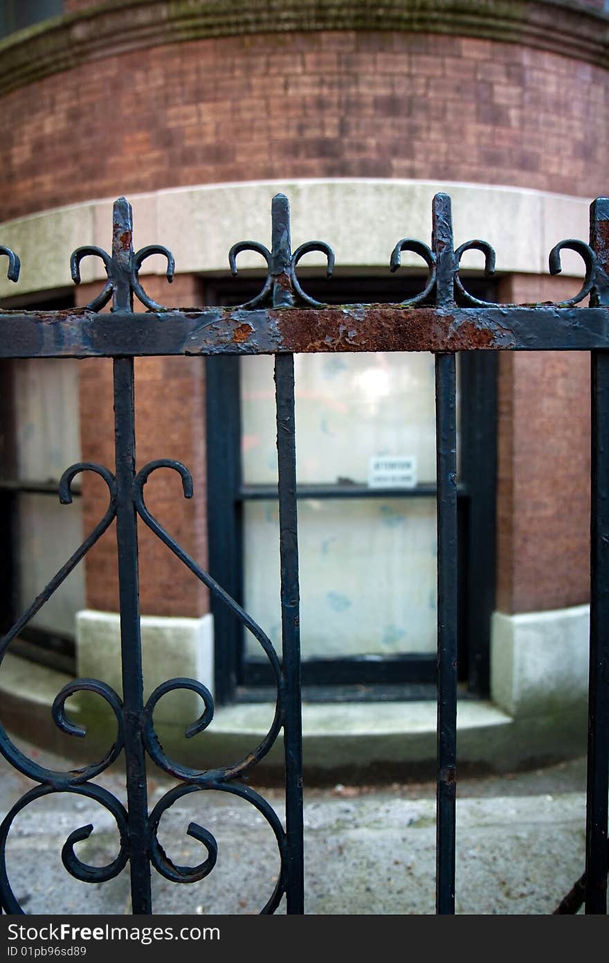 Rusted iron fence in front of a brownstone house in Brooklyn, with a window in the background. Rusted iron fence in front of a brownstone house in Brooklyn, with a window in the background