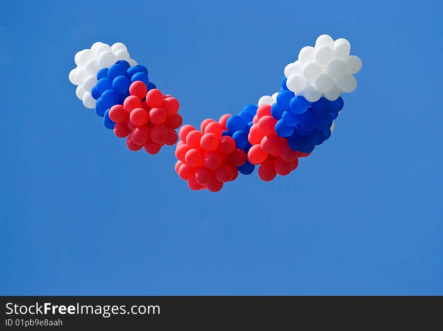 Red, white and blue balloons on a blue sky background