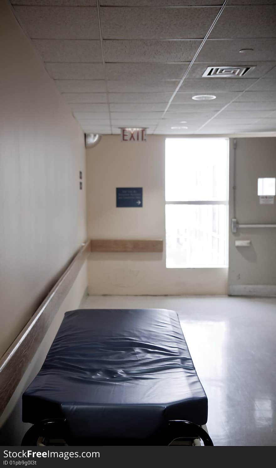 Uncovered stretcher at the hospital corridor with an emergency exit in the background