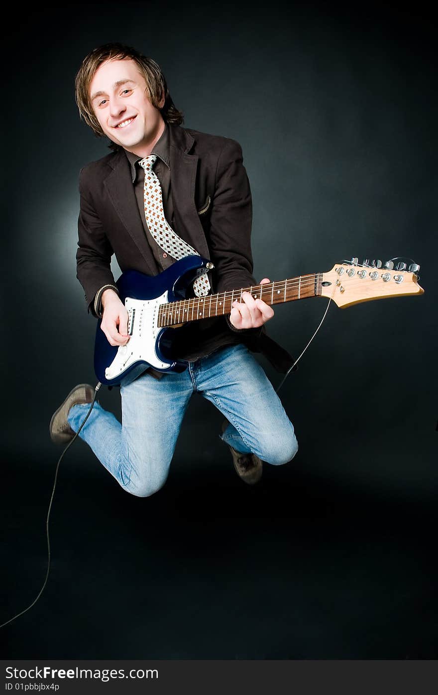 Jumping man with electro guitar, studio shot