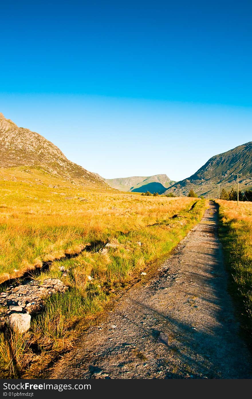 Path in Wales with  green fields and blue sky next to Tryfan. Path in Wales with  green fields and blue sky next to Tryfan