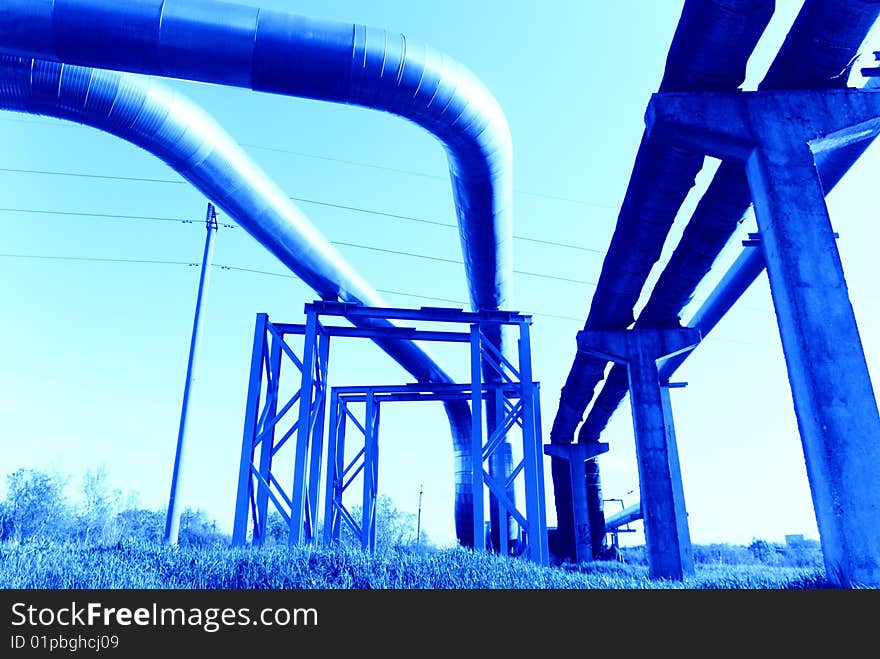 Industrial pipelines on pipe-bridge against blue sky. Industrial pipelines on pipe-bridge against blue sky.