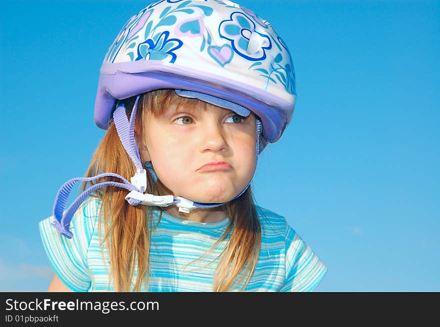 Grimacing girl with a helmet on her head on the blue background