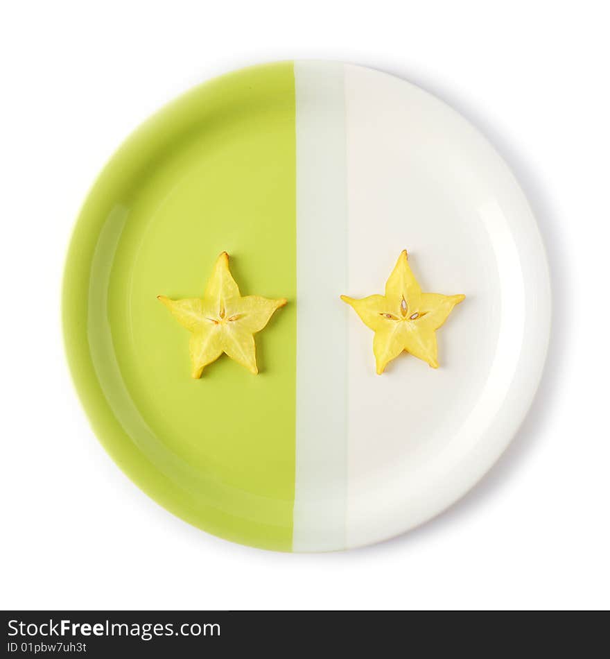 Two slices of starfruit (carambola) on a two-colored plate. Two slices of starfruit (carambola) on a two-colored plate