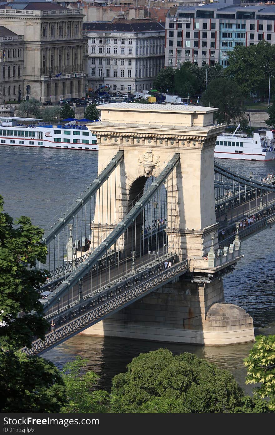 Széchenyi lánchíd or Szechenyi Chain Bridge is a suspension bridge that spans the River Danube between Buda and Pest, the western and eastern sides of Budapest, the capital of Hungary. It was the first permanent bridge across the Danube in Budapest, and was opened in 1849. The bridge had an enormous significance in the country's economics and life. Its decorations made of cast iron, and its construction, radiating calm dignity and balance, raised it among the most beautiful industrial monuments in Europe. It became a symbol of advancement, national awakening, and the linkage between East and West. Széchenyi lánchíd or Szechenyi Chain Bridge is a suspension bridge that spans the River Danube between Buda and Pest, the western and eastern sides of Budapest, the capital of Hungary. It was the first permanent bridge across the Danube in Budapest, and was opened in 1849. The bridge had an enormous significance in the country's economics and life. Its decorations made of cast iron, and its construction, radiating calm dignity and balance, raised it among the most beautiful industrial monuments in Europe. It became a symbol of advancement, national awakening, and the linkage between East and West.