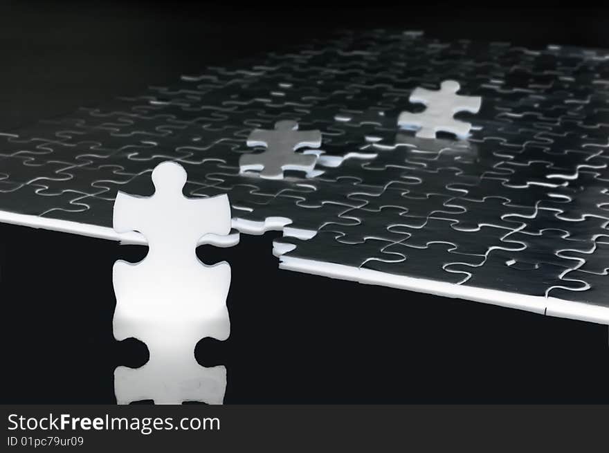 A standing piece of jigsaw puzzle infront of assembled puzzle. A standing piece of jigsaw puzzle infront of assembled puzzle