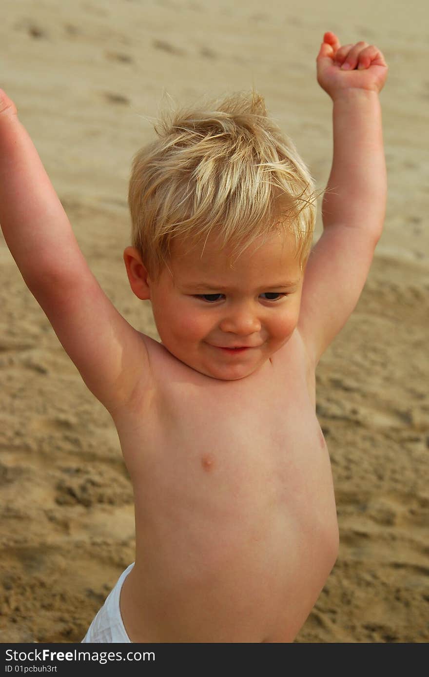 A little 2 year old boy holding his arms up in happiness. A little 2 year old boy holding his arms up in happiness