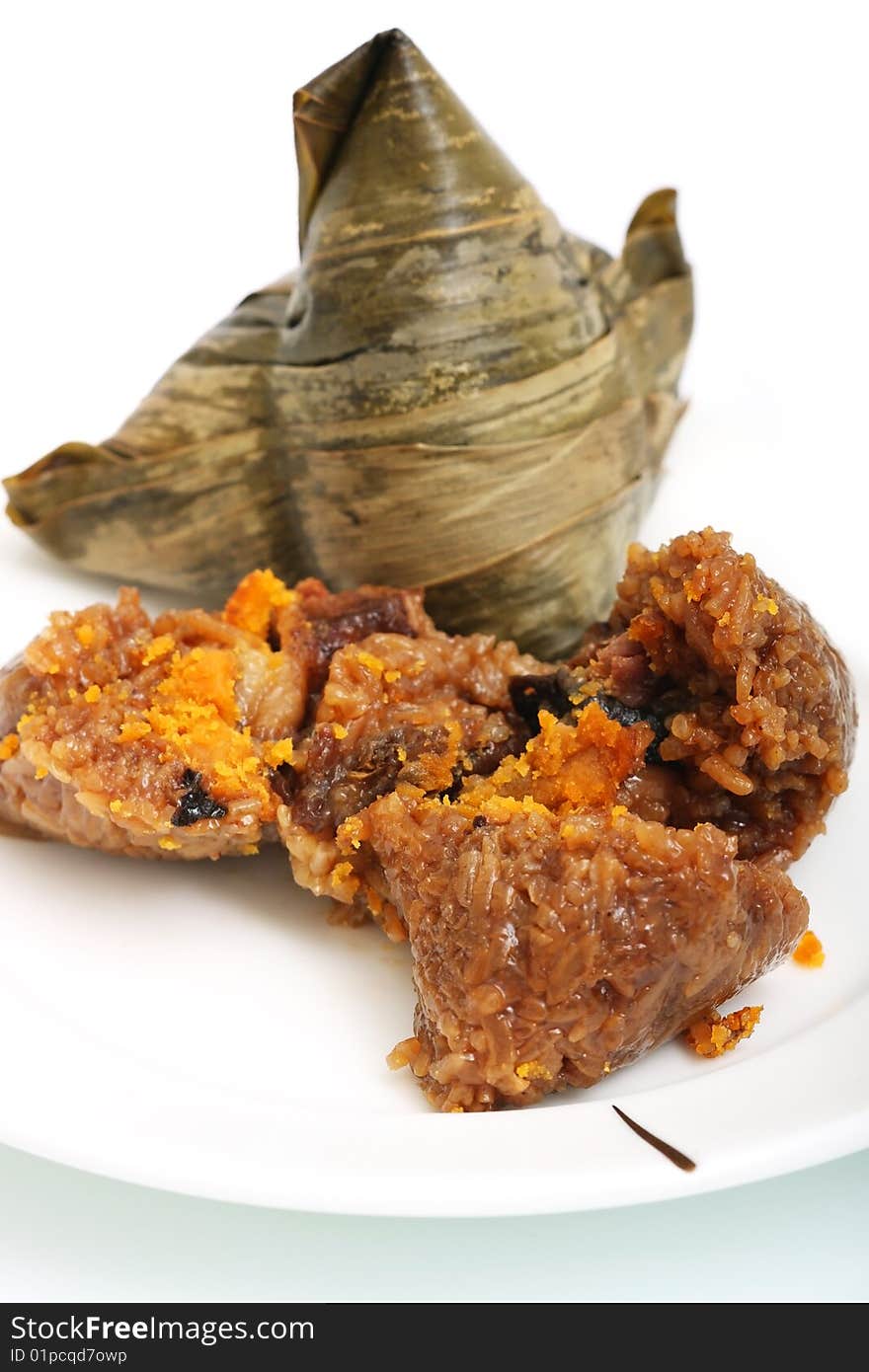 A unwrapped rice dumplings on plate over white background.