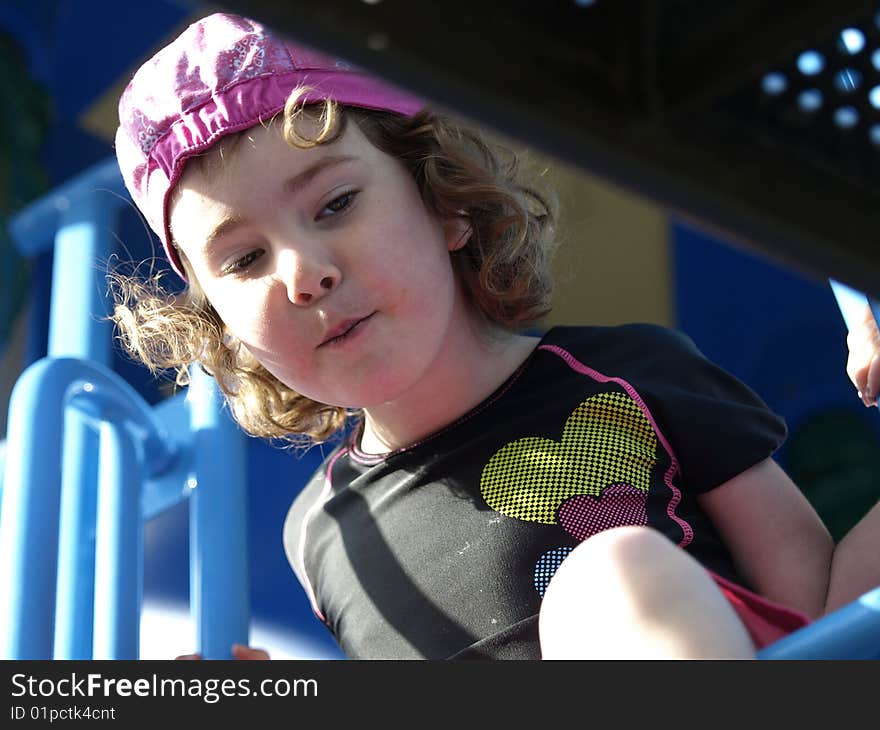 Young girl looking down from playground equipment having some innocent fun. Young girl looking down from playground equipment having some innocent fun.