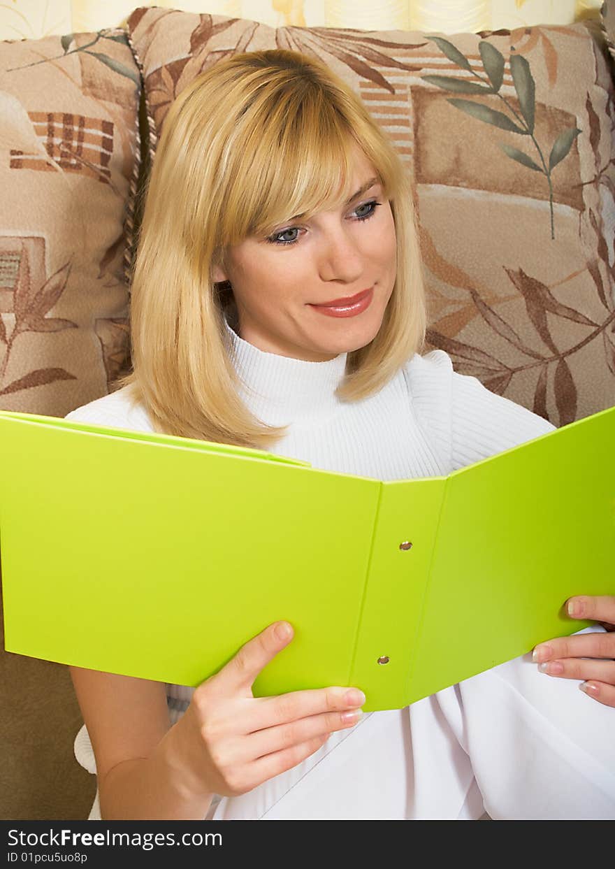 The beautiful girl sits at home with a folder for documents. The beautiful girl sits at home with a folder for documents