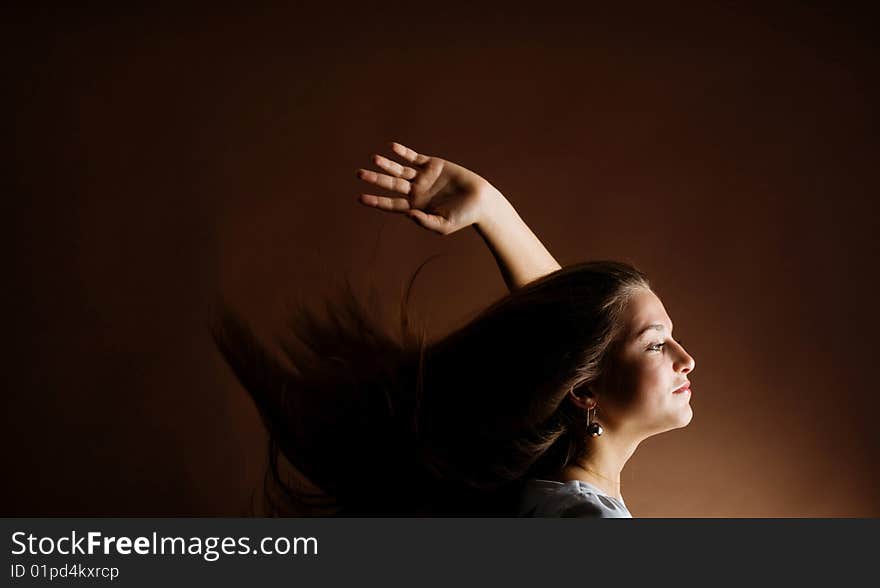 Fashion portrait of a young woman with hair lightly fluttering in the wind on a dark background. Fashion portrait of a young woman with hair lightly fluttering in the wind on a dark background