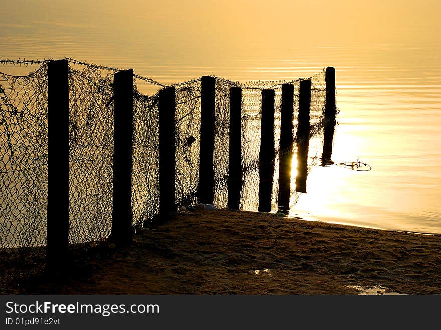 Fence shot on a shore of Dead Sea , Israel in sunrise light. Fence shot on a shore of Dead Sea , Israel in sunrise light