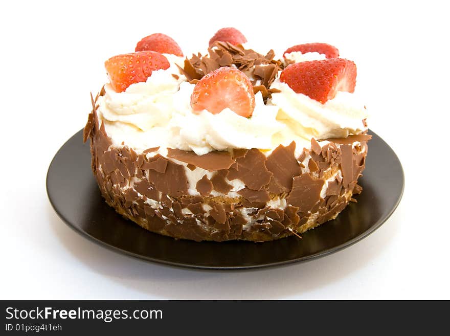 Whole strawberry gateau on a black plate with a white background