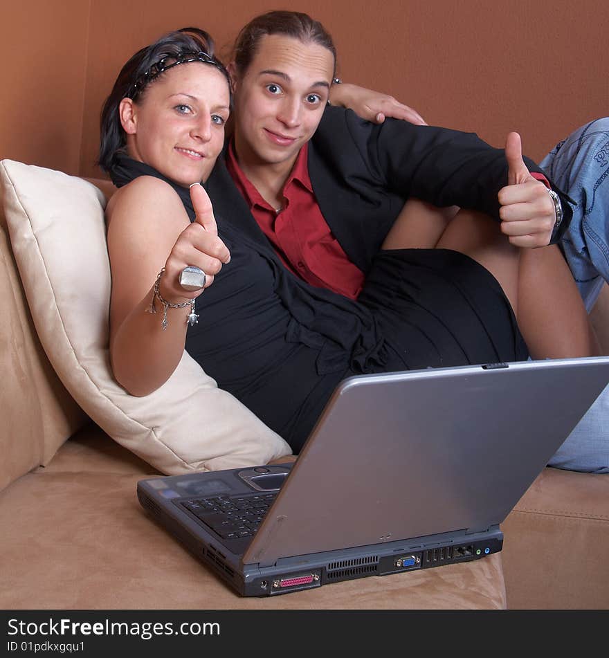 Young couple on the couch surfing the web with their laptop.