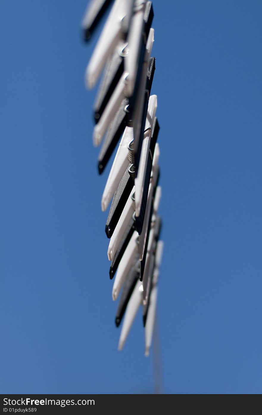 A row of black and white clothes pegs on a line with a blue sky background